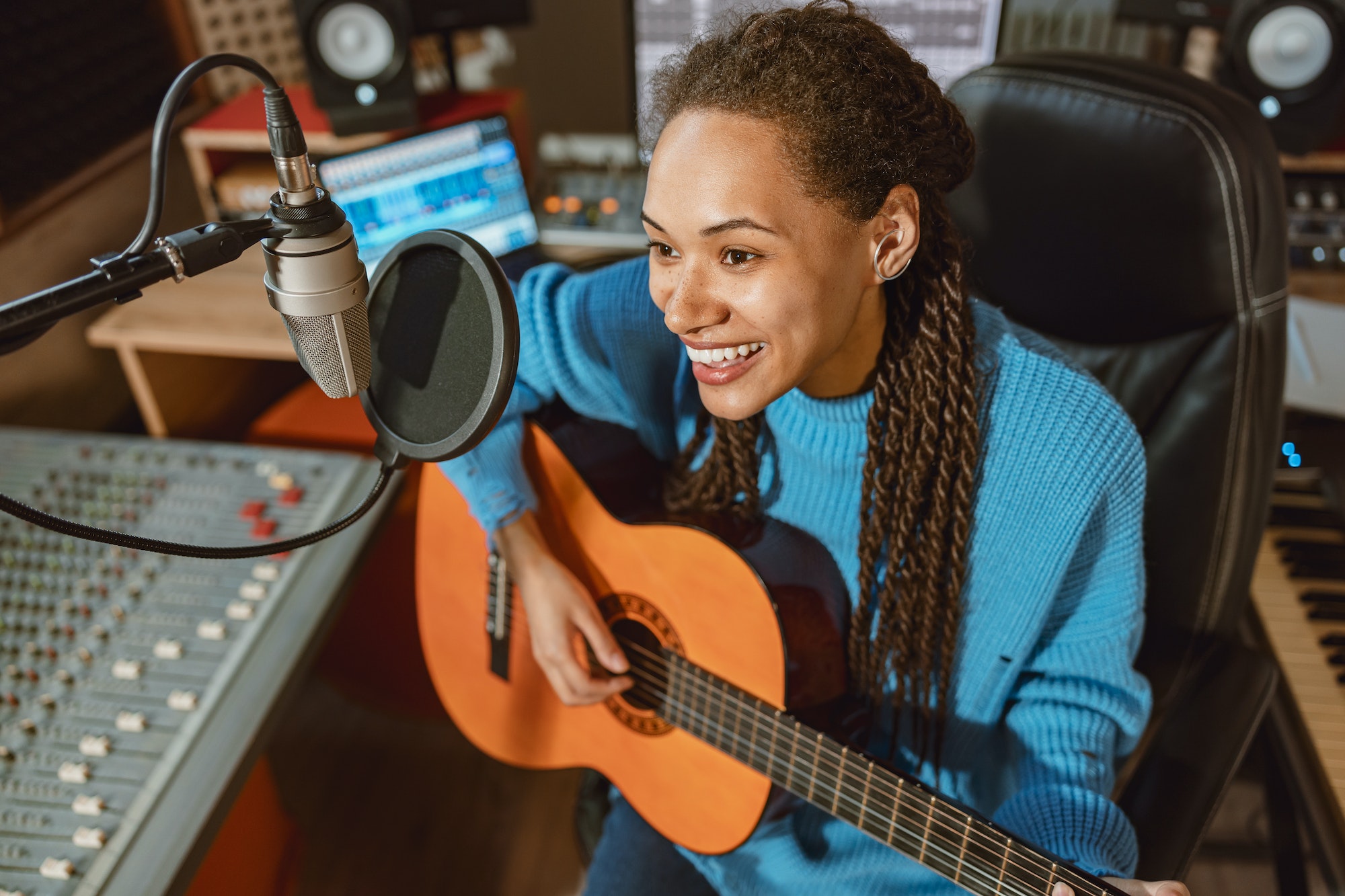 Passionate African American woman singer playing the guitar and recording song