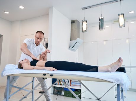 Young woman lying on medical couch while getting manual therapy session in medical office